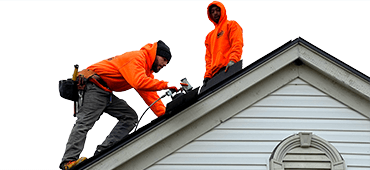 L&S team in bright orange working on a roof