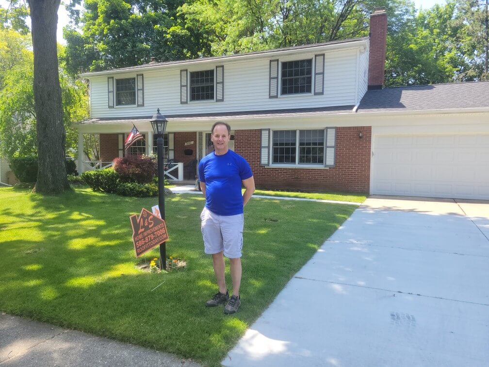 Photo of happy customer by L&S Home Improvements lawn sign in front of their home