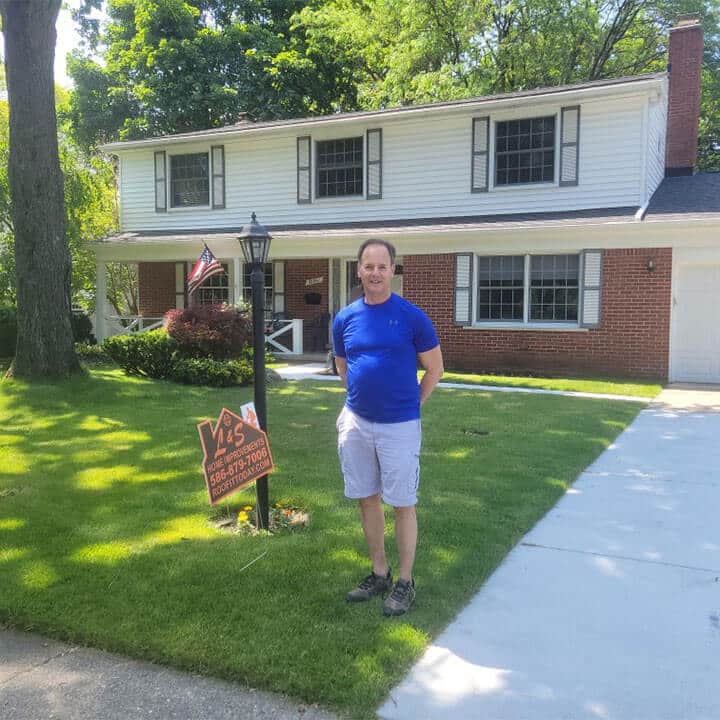 Photo of happy customer by L&S Home Improvements lawn sign in front of their home