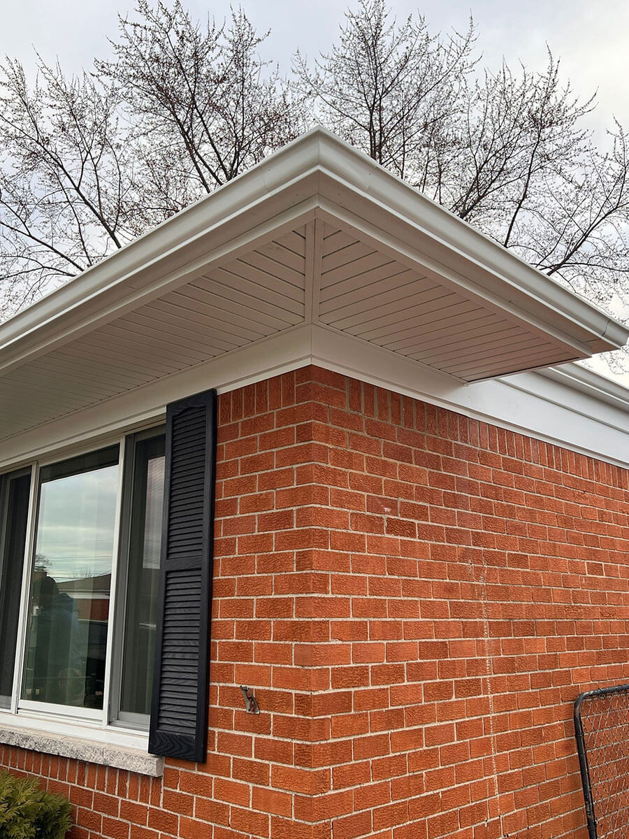 Corner of a home with new white, seamless gutters
