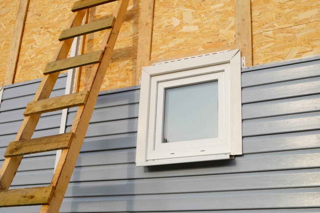 Grey-blue aluminum siding being installed on a home. 