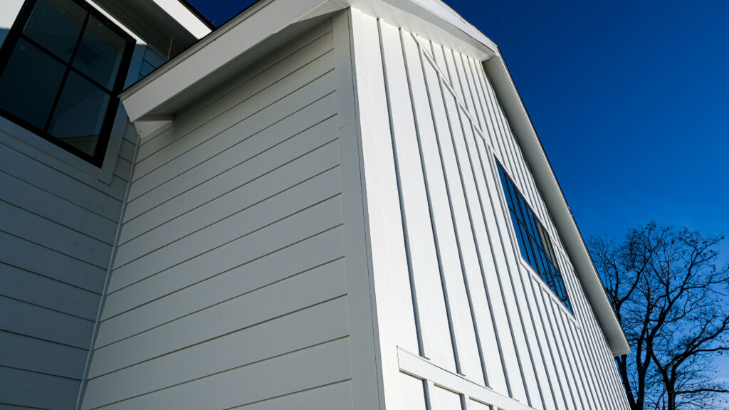 An upward angle of part of the front of a home. There is horizontal white fiber cement siding on the home.