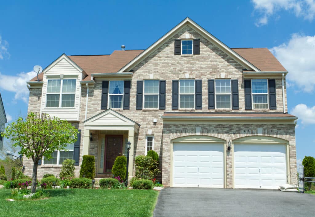 A two-story single-family home with tan and brown brick siding