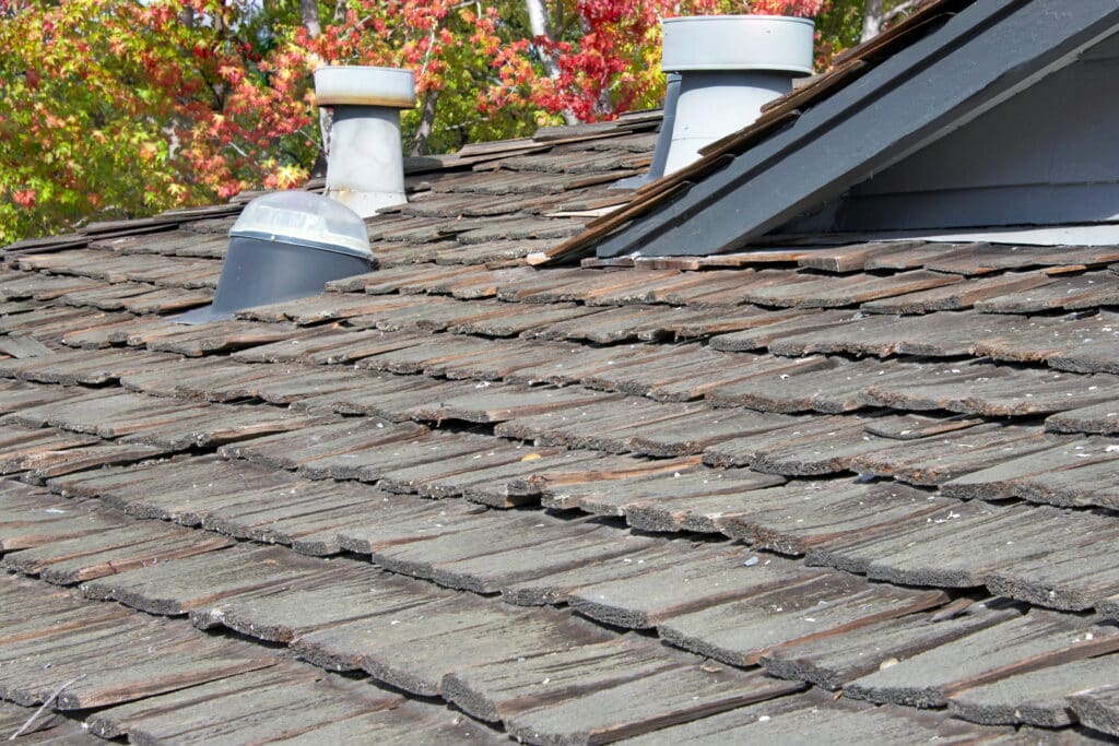 Cedar shake that is old and damaged. Some tiles have shifted or are chipped.