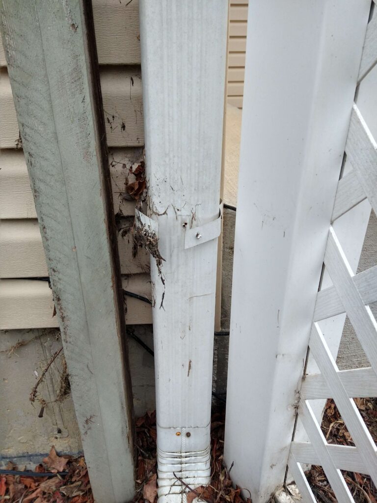 The joint to one section of a gutter system has popped out, showing an empty hole where the screw used to be that connected the joints together.