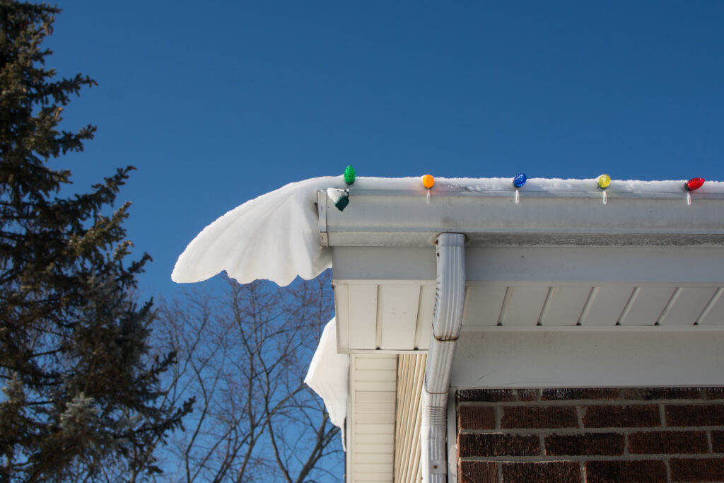 green, orange, blue, yellow, red holiday lights are clipped onto a gutter with plastic clips