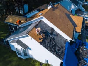 A drone shot of a worker installing shingles on plywood, an example of a tear-off