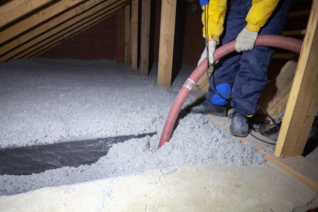 A person spraying cellulose insulation into attic baffles