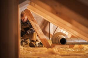 A man is installing insulation in an attic