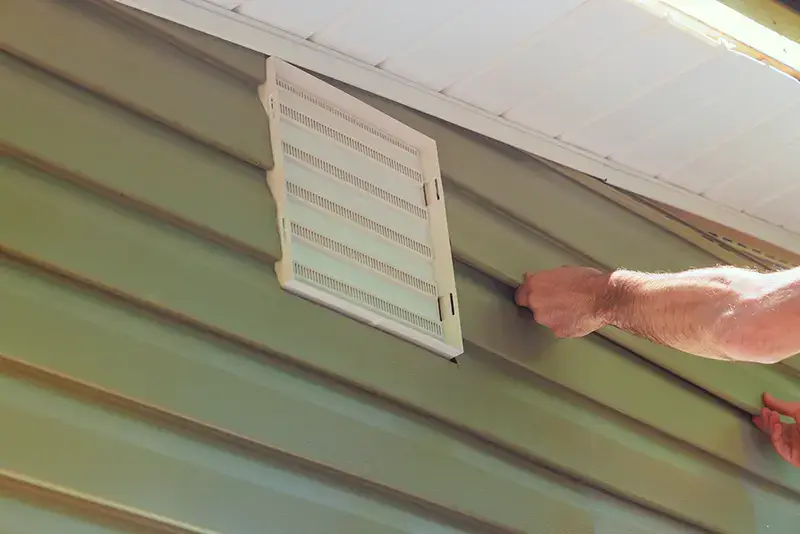 Wall facade of new house is covered with vinyl plastic siding panels installed by construction worker