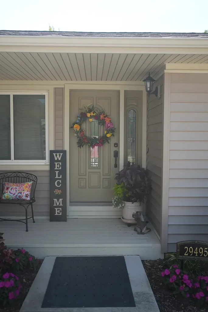 A decorated front door and porch with new siding